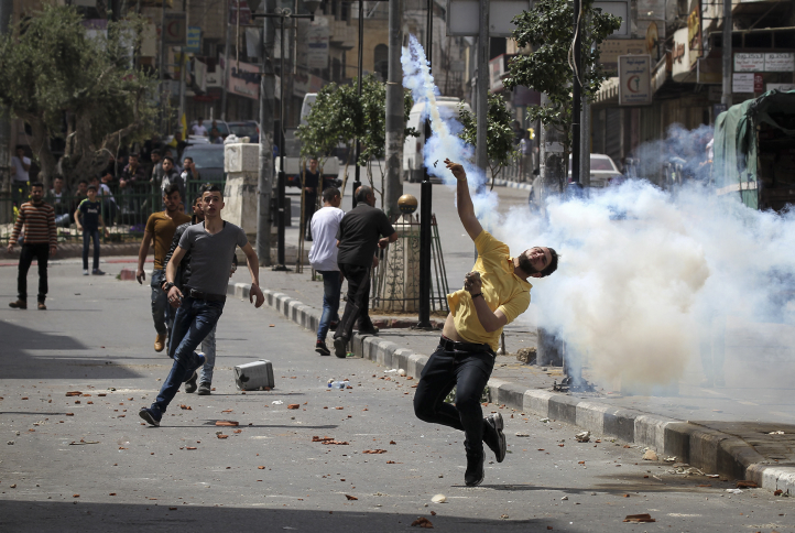 Palestinians throw stones and Israeli troops shoot tear gas and rubber-coated bullets at a protest in solidarity with hunger-striking Palestinian prisoners, Hebron, April 27, 2017. (Wisam Hashlamoun/Flash90)