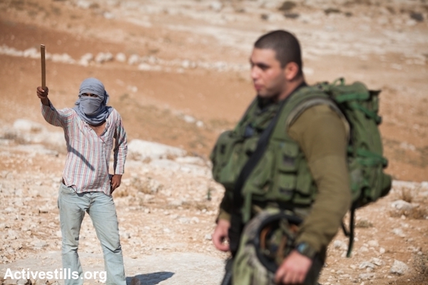 A masked Jewish settler in front of Ma'on settlement, South Hebron hills, September 22, 2012. (Yotam Ronen/Activestills.org)