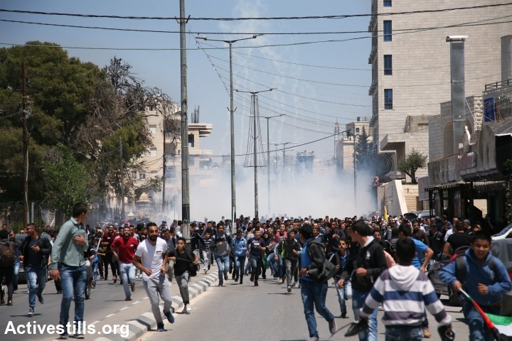 Hundreds of Palestinians protesting in support of hunger striking prisoners run tear gas shot by Israeli troops in Bethlehem, April 17, 2017. (Haidi Motola/Activestills.org)