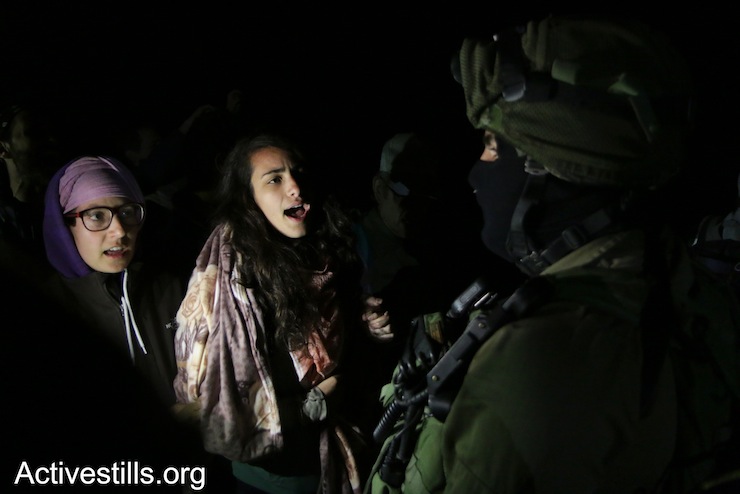 International Jewish activists chant in front of an Israeli soldier during a night raid on the Sumud Freedom Camp, Sarura, West Bank, May 20, 2017. (Ahmad al-Bazz/Activestills.org)