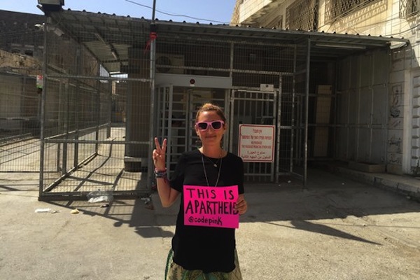 Jewish American activist Ariel Gold stands in front of an Israeli checkpoint in Hebron.
