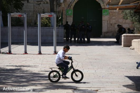 A Palestinian child rides his bike outside the Temple Mount/Haram al-Sharif. Israeli authorities erected metal detectors at the entrances to the compound in the wake of a deadly attack against Israeli security forces by three Palestinian citizens of Israel the week before. (Activestills.org)