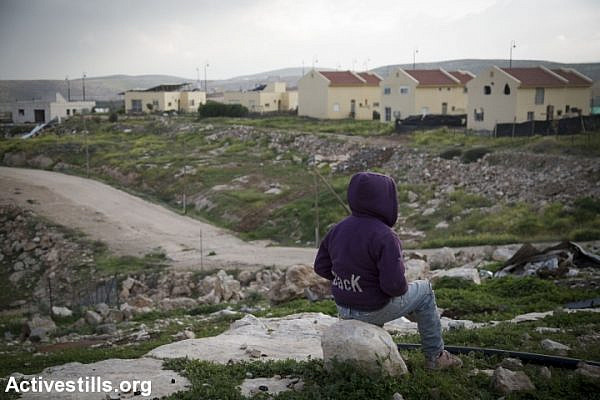 A Palestinian boy looks at the Israeli settlement of Carmel from the Bedouin village of Umm Al Khair, in South Hebron Hills, West bank, February 23, 2016. (Oren Ziv/Activestills.org)