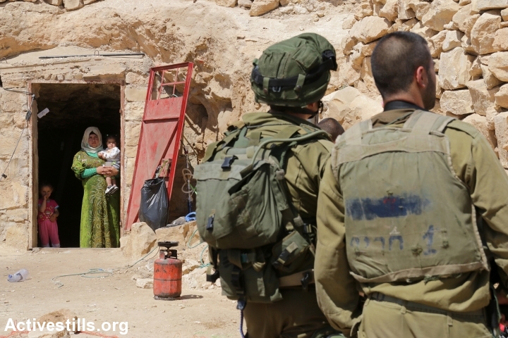 Israeli soldiers stand in front a cave in Sarura, where a Palestinian family lives, during the second military raid on Sumud Freedom Camp, May 25, 2017. (Ahmad al-Bazz/Activestills.org)