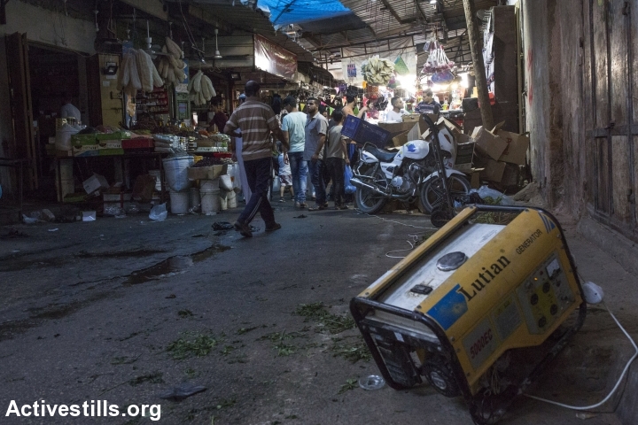 Palestinians walk past a gasoline-powered generator in the old market of Gaza City, Gaza Strip, June 9, 2017. (Anne Paq/Activestills.org)