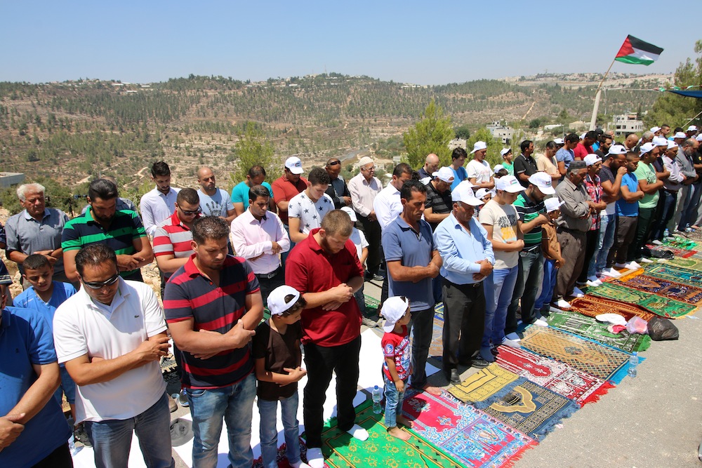 Dozens of Palestinians hold a mass prayer to protest the planned demolition of 14 buildings in their village of Walajeh, West Bank, August 18, 2017. (Ahmad Al-Bazz/Activestills.org)