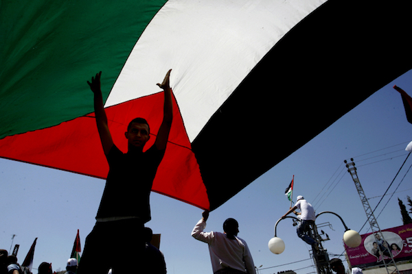 Palestinian youths hold up a large Palestinian flag. (Abed Rahim Khatib/Flash90)
