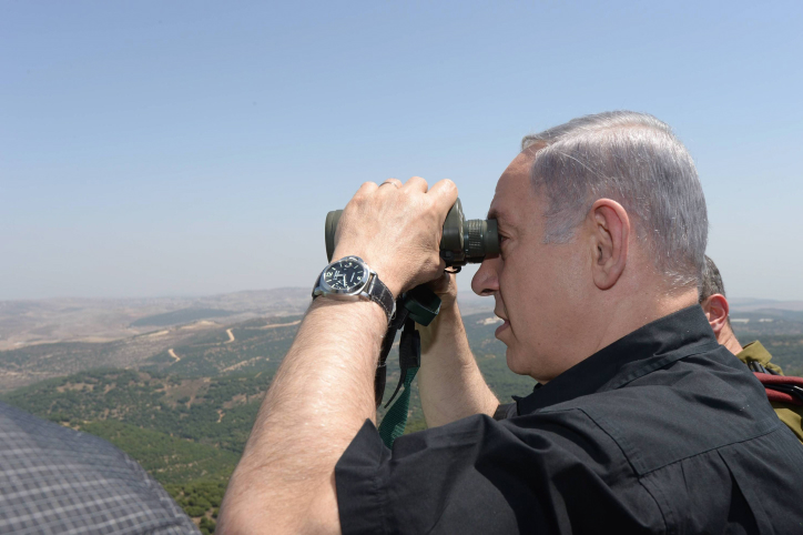 Israeli Prime Minister Benjamin Netanyahu looks through binoculars during his visit to the border with Syria, August 18, 2015. (Amos Ben Gershom/GPO)