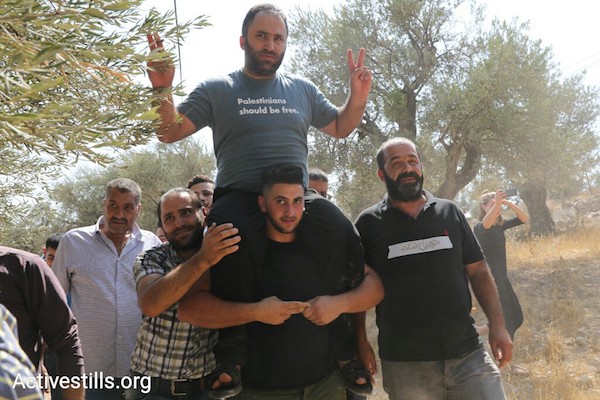 aPalestinian anti-occupation activists Issa Amro is carried on the shoulders of a fellow activist upon his release from Palestinian Authority custody in Hebron, September 10, 2017. (Oren Ziv/Activestills.org)