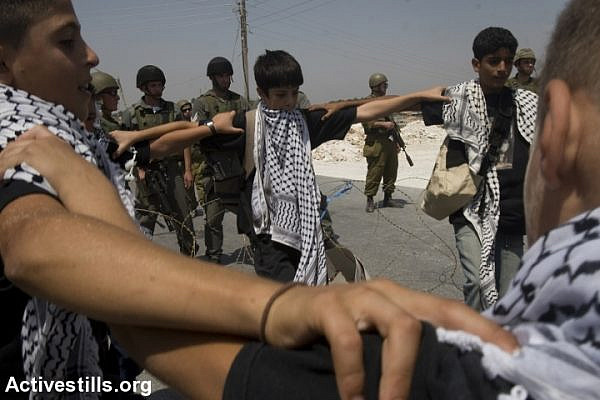 Palestinian youth perform a Dabke dance routine in front of soldiers during a protest against the separation wall, Al Ma'sara, West Bank, August 22, 2008. (Oren Ziv/Activestills.org)