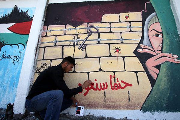 A Palestinian artist puts the final touches on a graffiti on a wall in Gaza City, May 8, 2010. The phrase is Arabic reads 'we will definitely come back.' (Wissam Nassar/Flash90)