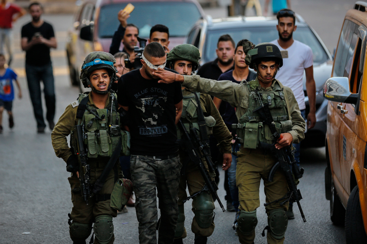 Israeli soldiers arrest a Palestinian man during a raid on the West Bank city of Hebron, September 20, 2017. (Wisam Hashlamoun/Flash90)