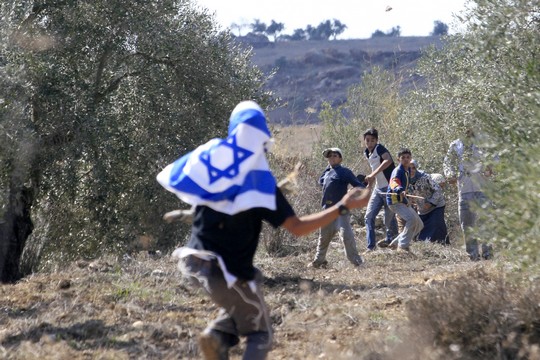 An Israeli settler, masked with an Israeli flag, and Palestinian boys throw stones during clashes at an olive harvest close near Nablus, Wednesday 25, 2006. (Olivier Fitoussi/Flash90)