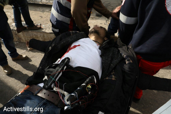 A Palestinian man with an explosive belt is seen carried by paramedics after being shot by Israeli soldiers during clashes at the DCO Checkpoint, Beit El, West Bank. The man attempted to stab Israeli soldiers shooting tear gas at the demonstrators. Upon falling to the ground, he revealed an explosive belt strapped to his body. (Oren Ziv/Activestills.org)