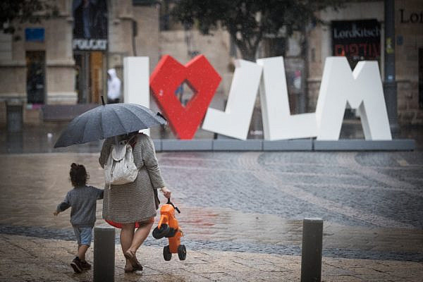 People hold umbrellas to protect themselves from the rain as they walk on Jaffa Street in downtown Jerusalem, October 9, 2017, (Yonatan Sindel/Flash90)