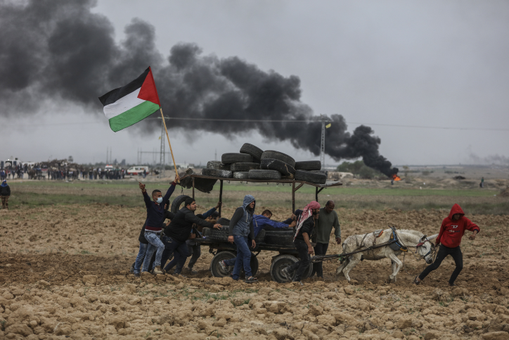 Palestinian protesters chant as they surround a donkey cart loaded with tires during clashes with Israeli troops on the Israeli border with Gaza. December 22, 2017. (Wissam Nassar/Flash90)