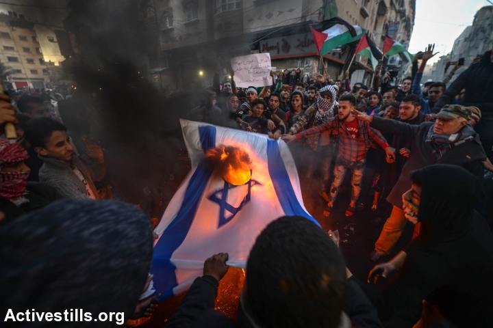 Palestinians burn an Israeli flag during a protest against the U.S. President Donald Trump's declaration to recognize Jerusalem as the capital of Israel, Gaza City, Gaza Strip, December 7, 2017. (Ezz Zanoun/Activestills.org)