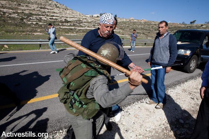 An Israeli Border Police officer beats a Palestinian protester with a club during a demonstration in Nabi Saleh, January 15, 2010. (Yotam Ronen/Activestills.org)
