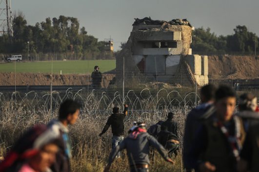 Palestinian protesters inside the Gaza Strip throw stones in the direction of an Israeli military position on the other side of the border fence, Gaza Strip, December 8, 2017. (Ezz Zanoun/Activestills.org)