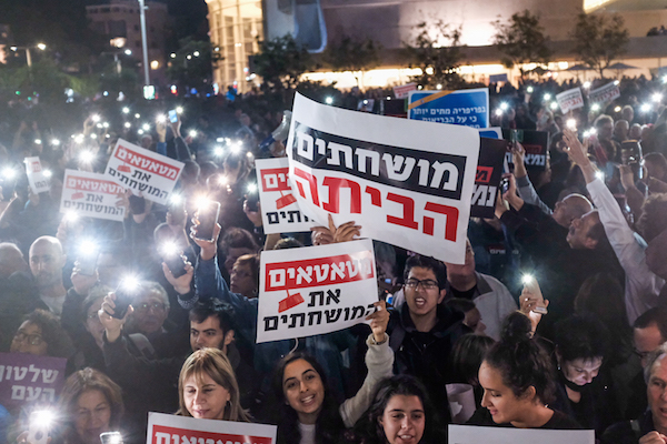 Israelis holding signs and shout slogans during a protest against the corruption of the government in Tel Aviv on December 9, 2017. (Tomer Neuberg/Flash90)