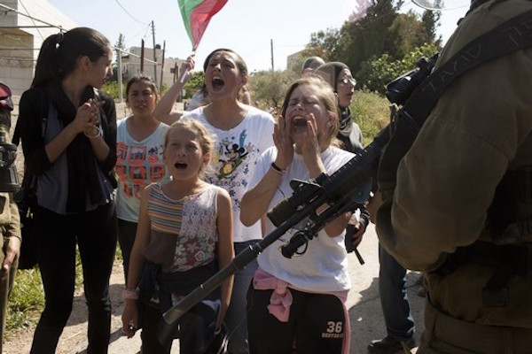 Palestinian children and women face Israeli soldiers during the weekly protest against the occupation in the west Bank village of Nabi Saleh, April 20, 2012. (Activestills)