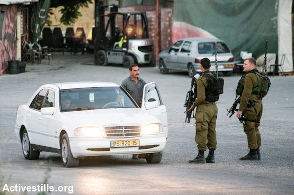 Israeli soldiers stop Palestinians at a flying checkpoint at the entrance to the West Bank city of Hebron, June 15, 2014. (Yotam Ronen/Activestills.org)