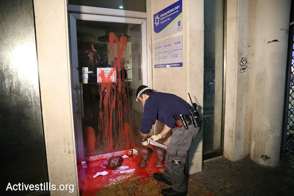 A policeman surveys the results of a protest action outside of the Population and Immigration Authority's office in Tel Aviv on Saturday, January 27, 2018. (Oren Ziv/Activestills.org)