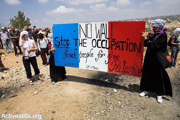 Women activisits hold up signs during an action that attempts to dismantle a barbed wire part of the gate of the Seperation Wall in Bil'in, as part of the weekly protest against the Separation Wall and the occupation, West Bank, August 14, 2009. Hundreds of Palestinians, Israeli, and international activists, responded to the Popular Committee's call to resist to participate in the action. (Yotam Ronen/Activestills.org)