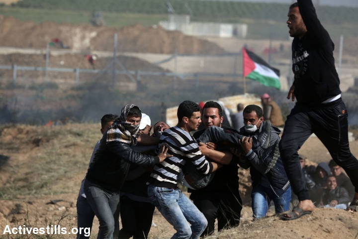 Palestinian protesters evacuate a fellow demonstrator who was shot by an Israeli sniper during the Great Return March protest, east of Jabaliya, Gaza Strip, April 6, 2018. (Mohammed Zaanoun/Activestills.org)