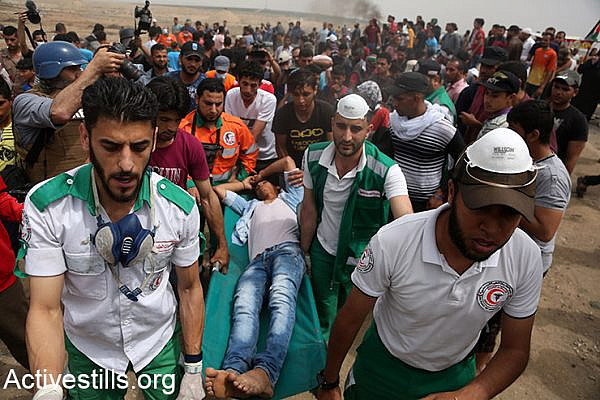 Palestinian medics carry a demonstrator on a stretcher during the Great March of Return protests, May 4, 2018. (Mohammed Zaanoun/Activestills.org)