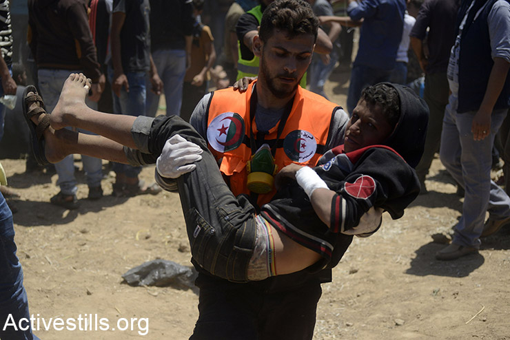 A medic carries a Palestinian child during a protest in the Gaza Strip, as part of the Great March of Return, May 14, 2018. (Mohammed Zaanoun/Activestills.org)