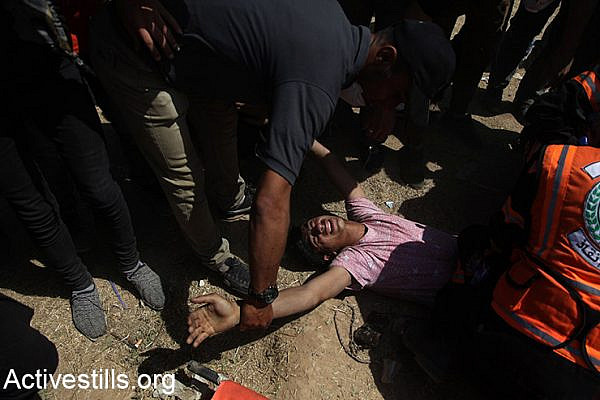 Medics help a wounded Palestinian during demonstrations on the Gaza border, May 14, 2018. (Mohammed Zaanoun/Activestills.org)