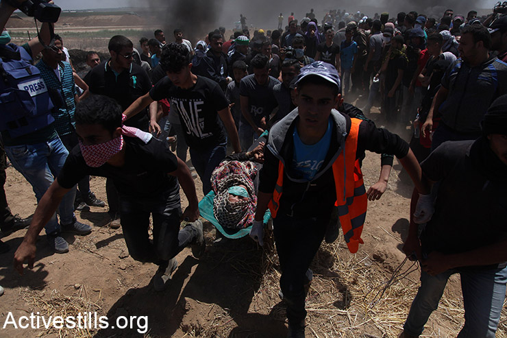 Medics evacuate a Palestinian protester who was shot by Israeli snipers during protests inside the Gaza Strip, May 14, 2018. (Mohammed Zaanoun/Activestills.org)