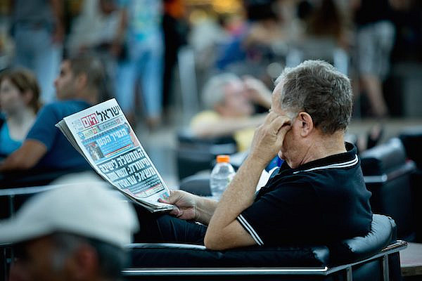 Illustrative photo of a man reading "Israel Hayom," the Sheldon Adelson-funded newspaper (Moshe Shai/FLASH90).
