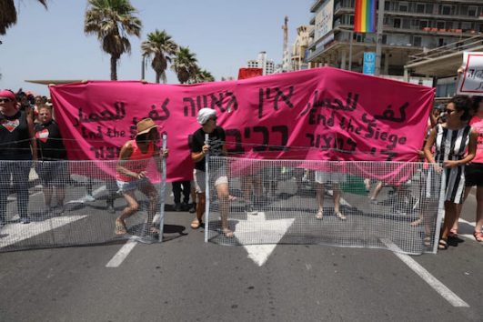 Israeli LGBTQ activists block the Tel Aviv Pride March. The sign says "there's no pride in occupation" and "end the siege." June 8, 2018. (Yael Marom)