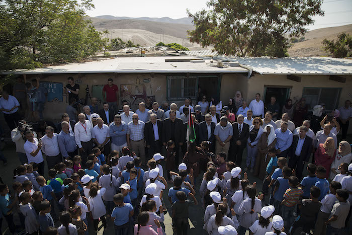 Palestinian leaders, including the PA minister of education and MK Ahmad Tibi, welcome the schoolchildren of Khan al-Ahmar on the first day of the school year, which was pushed back by a month and a half to stop the demolition of the village, July 16, 2018. (Oren Ziv)