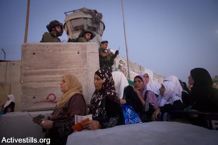 Israeli soldiers watch Palestinian women walk towards Qalandiya checkpoint, West Bank, August 20, 2010. (Oren Ziv/Activestills.org)