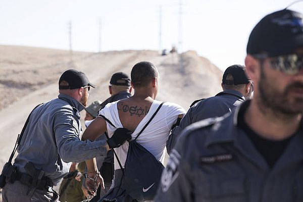 Israeli police arrest an international solidarity activist who had attempted to block a bulldozer brought to prepare for the demolition of Khan al-Ahmar, July 5, 2018. (Oren Ziv/Activestills.org)