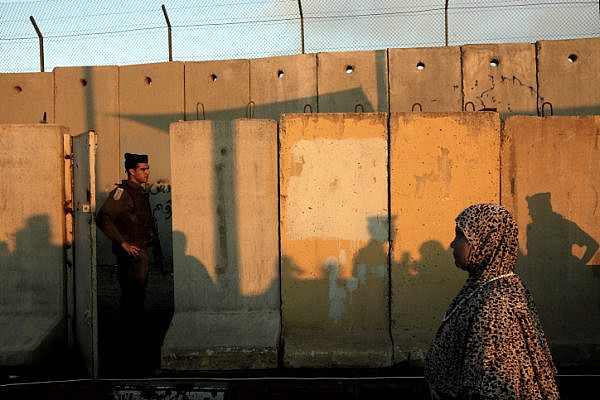 A Muslim Palestinian worshipper headed to the Al-Aqsa compound in Jerusalem walks by an Israeli soldier as she crosses the Qalandia checkpoint on August 05, 2011 (Miriam Alster/ Flash90).