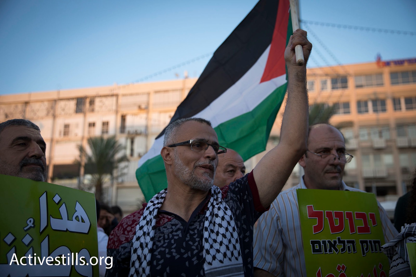 A Palestinian citizen of Israel waves a Palestinian flag during a protest against the Jewish Nation-State Law, central Tel Aviv, August 12, 2018. (Oren Ziv/Activestills.org)