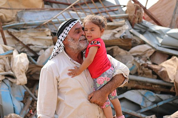 A Palestinian man plays with his daughter in front of his residential structure following an Israeli demolition in Al Hadidiya, Jordan Valley, West Bank, October 11, 2018. (Ahmad al-Bazz/Activestills.org)