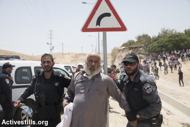 Israeli policemen arrest a Palestinian protester, as demonstrators try to prevent an Israeli army bulldozer from laying the groundwork for the demolition of Khan al-Ahmar, West Bank, July 4, 2018. (Oren Ziv/Activestills.org)