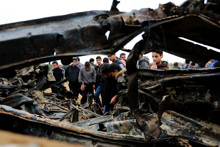 Palestinians stand next to the remains of a car destroyed during fighting between Hamas militants and Israeli special forces in Khan Younis in the Gaza Strip, November 12, 2018. (Abed Rahim Khatib/Flash90)