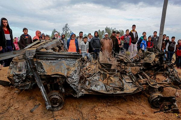 Palestinians stand next to the remains of a car destroyed during fighting between Hamas militants and Israeli special forces in Khan Younis, Gaza Strip, November 12, 2018. (Abed Rahim Khatib/Flash90)