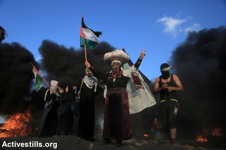 Palestinian protesters waive the Palestinian flag, during a Great Return March demonstration near the Gaza-Israel fence, Gaza Strip, September 7, 2018. (Mohammed Zaanoun/Activestills.org)