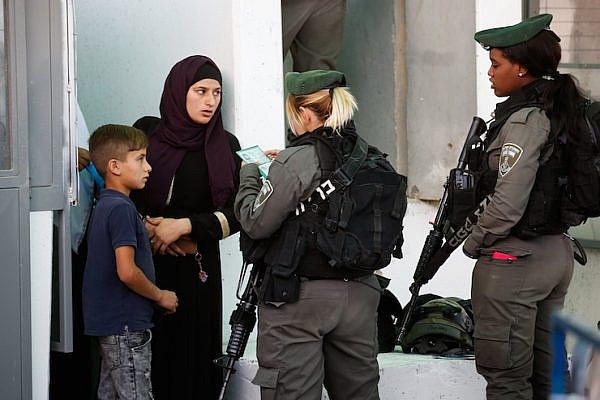 Israeli troops check the ID of a Palestinian woman and her child at a checkpoint in the occupied West Bank, May 18, 2018. (Wisam Hashlamoun/Flash90)