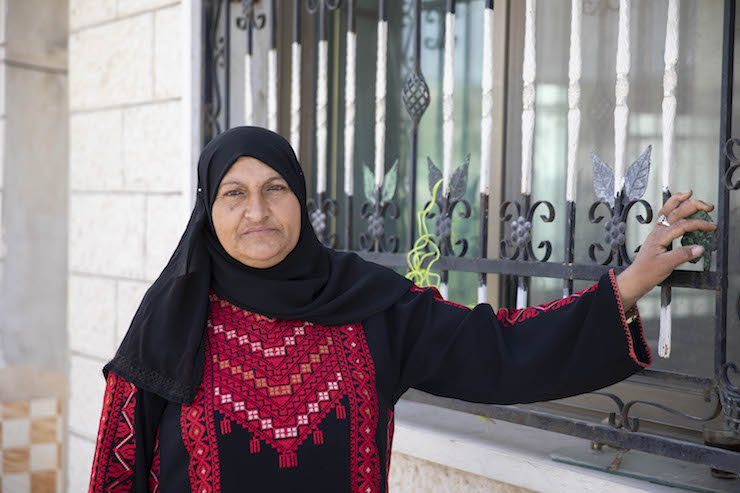 A Palestinian woman seen outside her home in the West Bank village of Urif. She has installed two layers of metal bars to protect her home from settler attacks. (Oren Ziv/Activestills.org)