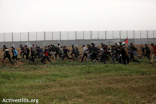 A large group of protesters runs from Israeli sniper fire and crowd control measures, east of Gaza City, March 30, 2019. (Mohammed Zaanoun/Activestills.org)