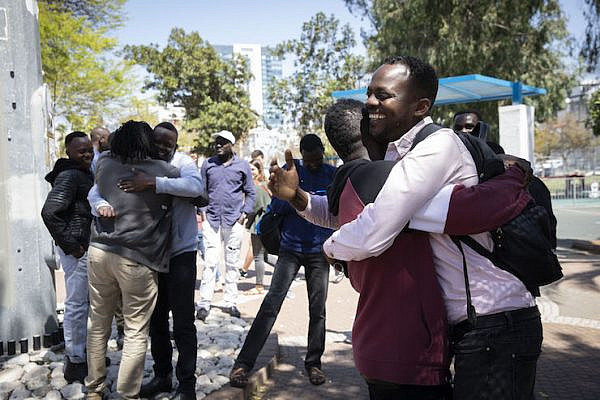 Sudanese asylum seekers embrace in south Tel Aviv's Levinksy Park following the announcement that Omar al-Bashir will step down after 30 years in power,  April 11, 2019. (Oren Ziv/Activestills.org)