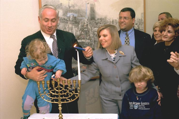 Prime Minister Benjamin Netanyahu lights Hanukkah candles alongside his wife Sara and their children during his first term as prime minister, December 5, 1996. (GPO)